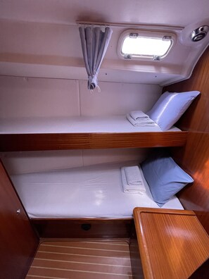 Una cabaña con dos literas, una ventana con cortinas y una pequeña mesa.