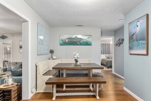 A dining area with a wooden table and benches, a whiteboard, and a framed fish painting on the wall. - Lake Rousseau Sunsets from Screen Porch + Firepit (Dunnellon)