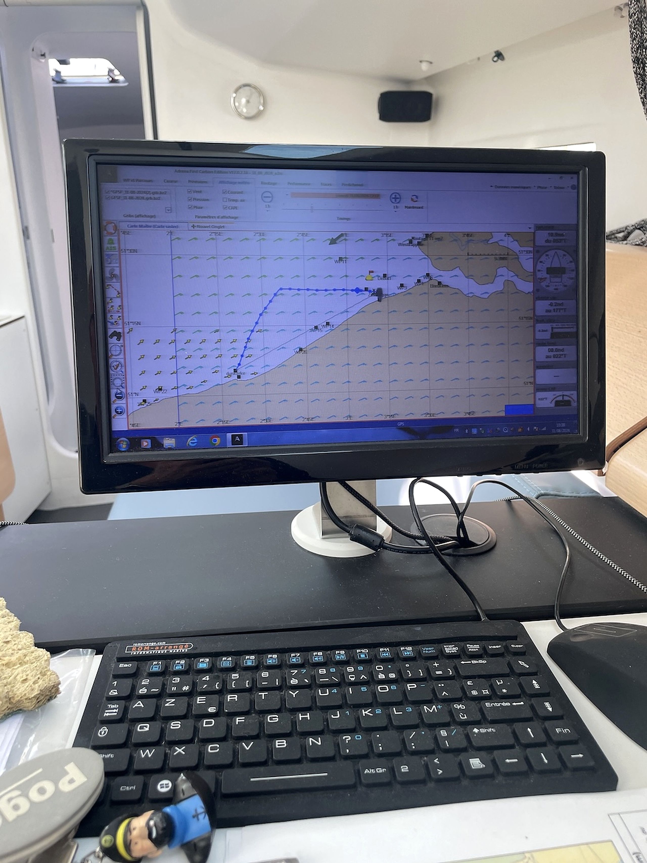 En computerskærm viser et vejr kort, et tastatur og en mus på et skrivebord.