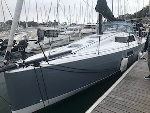 A sailboat docked at a marina with other boats and a person standing on the dock.