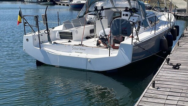 Un port de plaisance avec des bateaux amarrés, un ciel dégagé et un drapeau flottant sur l’un des bateaux.