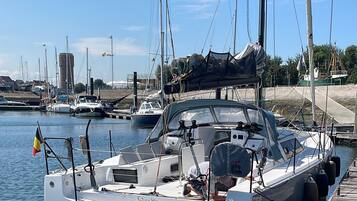Un port de plaisance avec des bateaux amarrés, un ciel dégagé et un drapeau flottant sur l’un des bateaux.