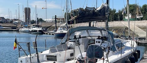 A marina with boats docked, a clear sky, and a flag on one boat.