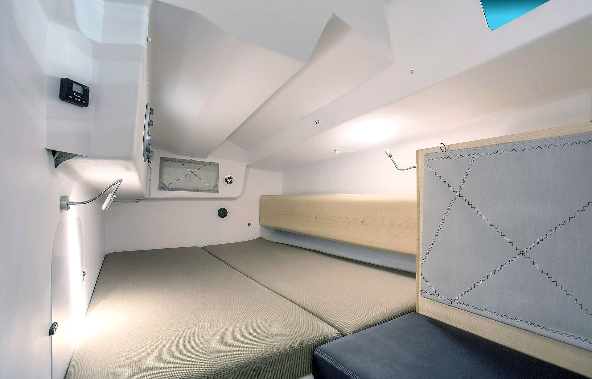 En kompakt og veloplyst hytte med en enkeltseng, et lille bord og et panel til styring på væggen.