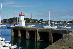 A harbor with boats, a lighthouse, and houses in the background.