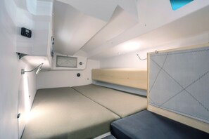 A compact, modern interior with a bunk bed, a small table, and a wall-mounted control panel.