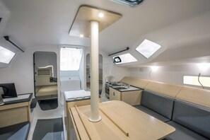 A compact RV interior with a kitchenette, seating area, and a central column with a light fixture.