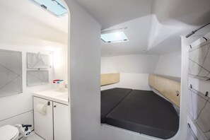 Ein kompakter, gut beleuchteter Innenraum mit kleinem Badezimmer, Schlafbereich mit Matratze und Dachfenster.