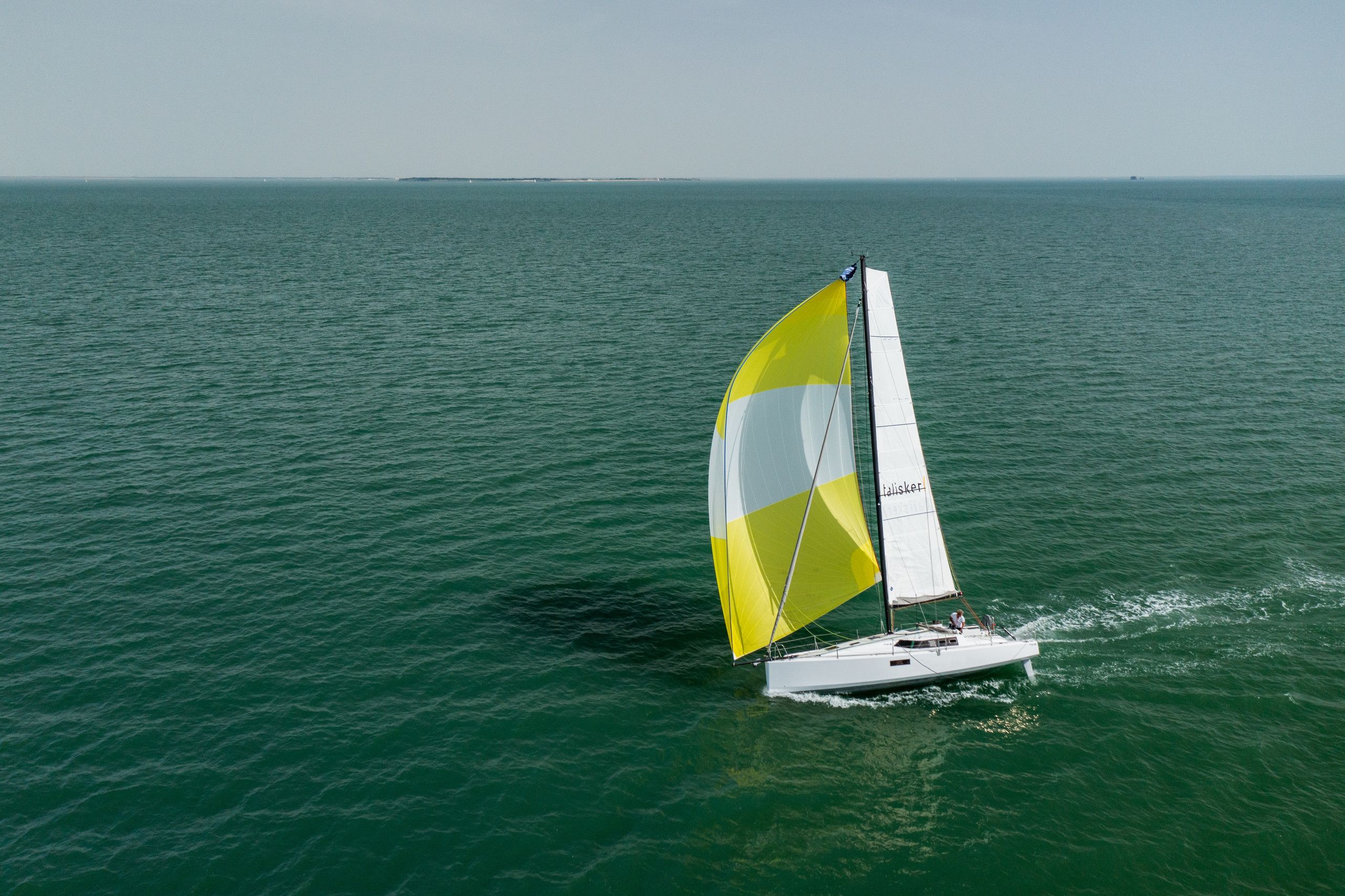 Una barca a vela con una vela gialla e bianca sull'acqua.