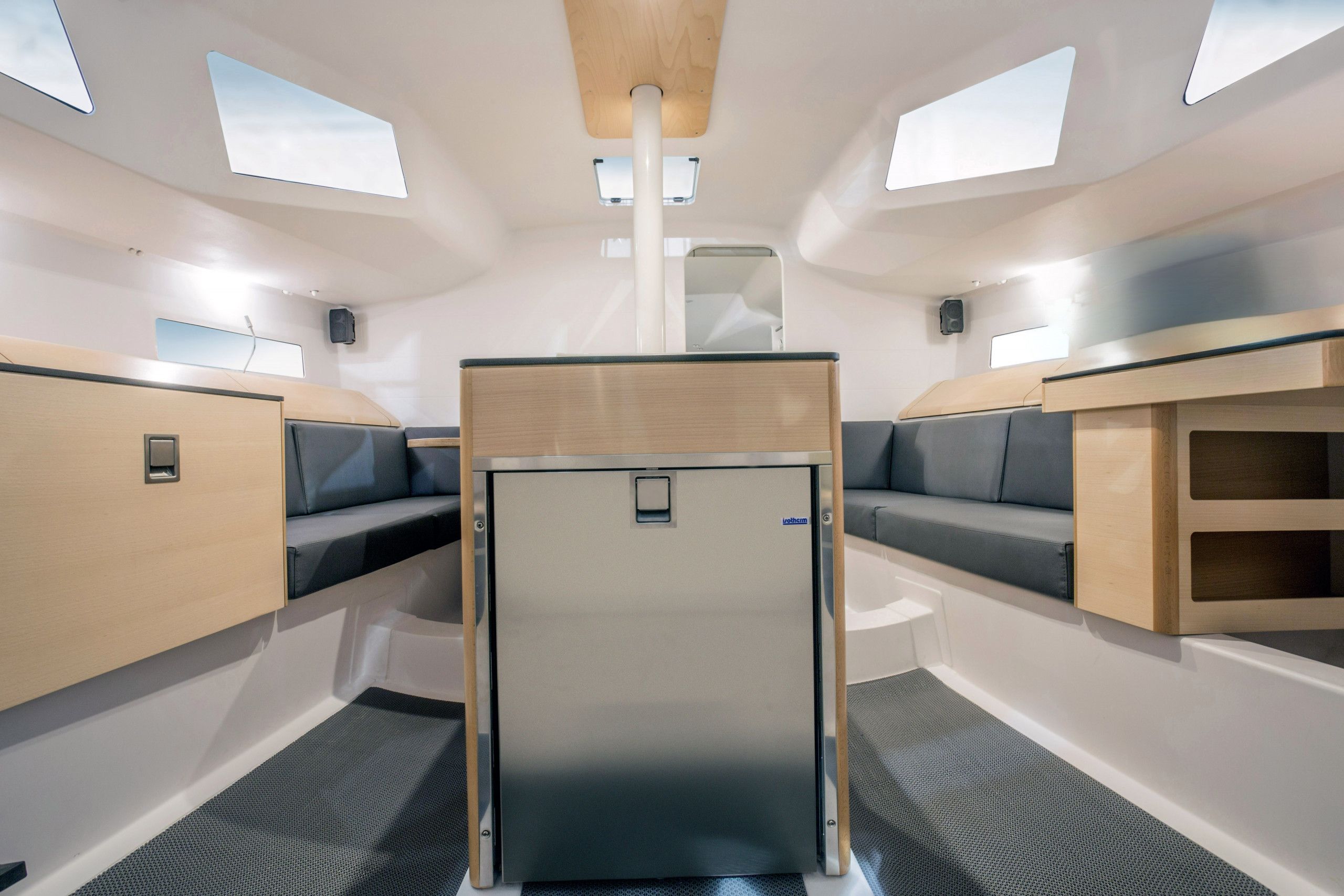 Un intérieur compact comprenant un espace salon central, une petite kitchenette et des fenêtres de toit.
