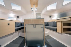A compact interior with a central seating area, a small kitchenette, and skylights.