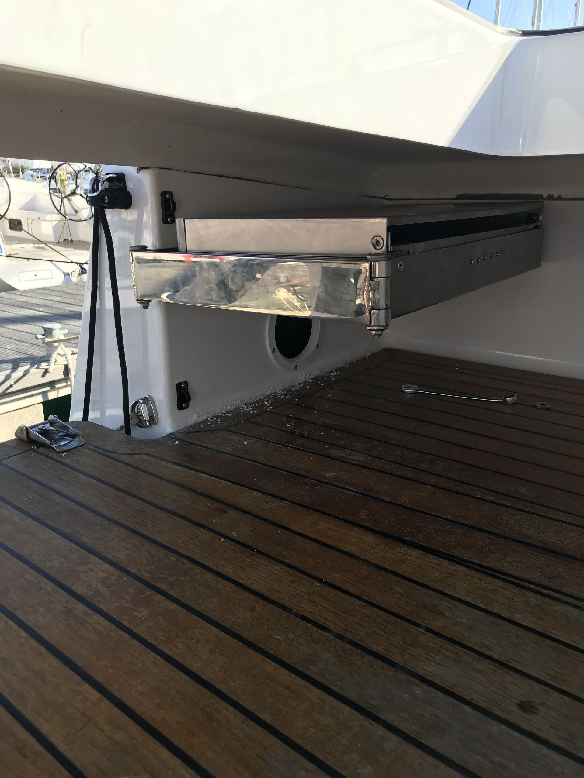 A metallic bracket attached to a boat's hull, a small circular opening, and a wooden deck.