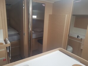 A compact, well-lit room with a bunk bed, a small bathroom with a toilet and sink, and a mirror above the sink.