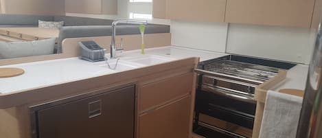 A compact kitchen with a sink, stove, and storage cabinets.