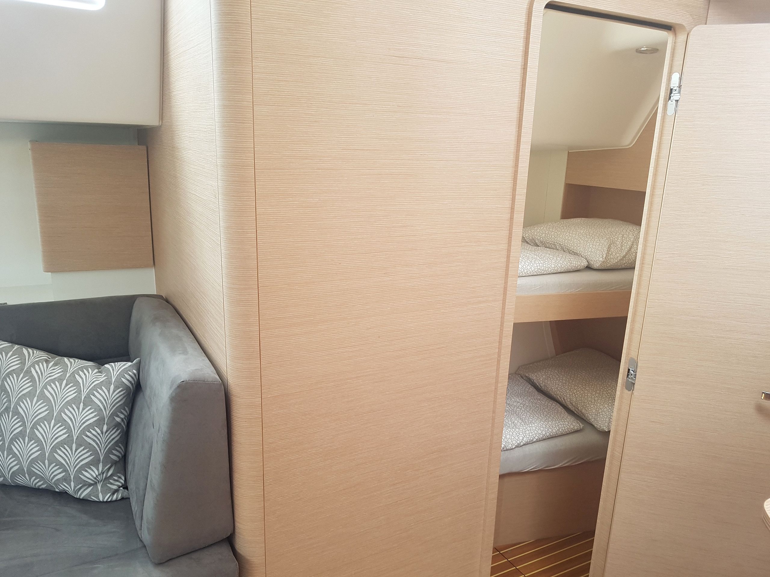 Habitació petita amb un llit superposat, un sofà amb coixinets estampats i una porta.
