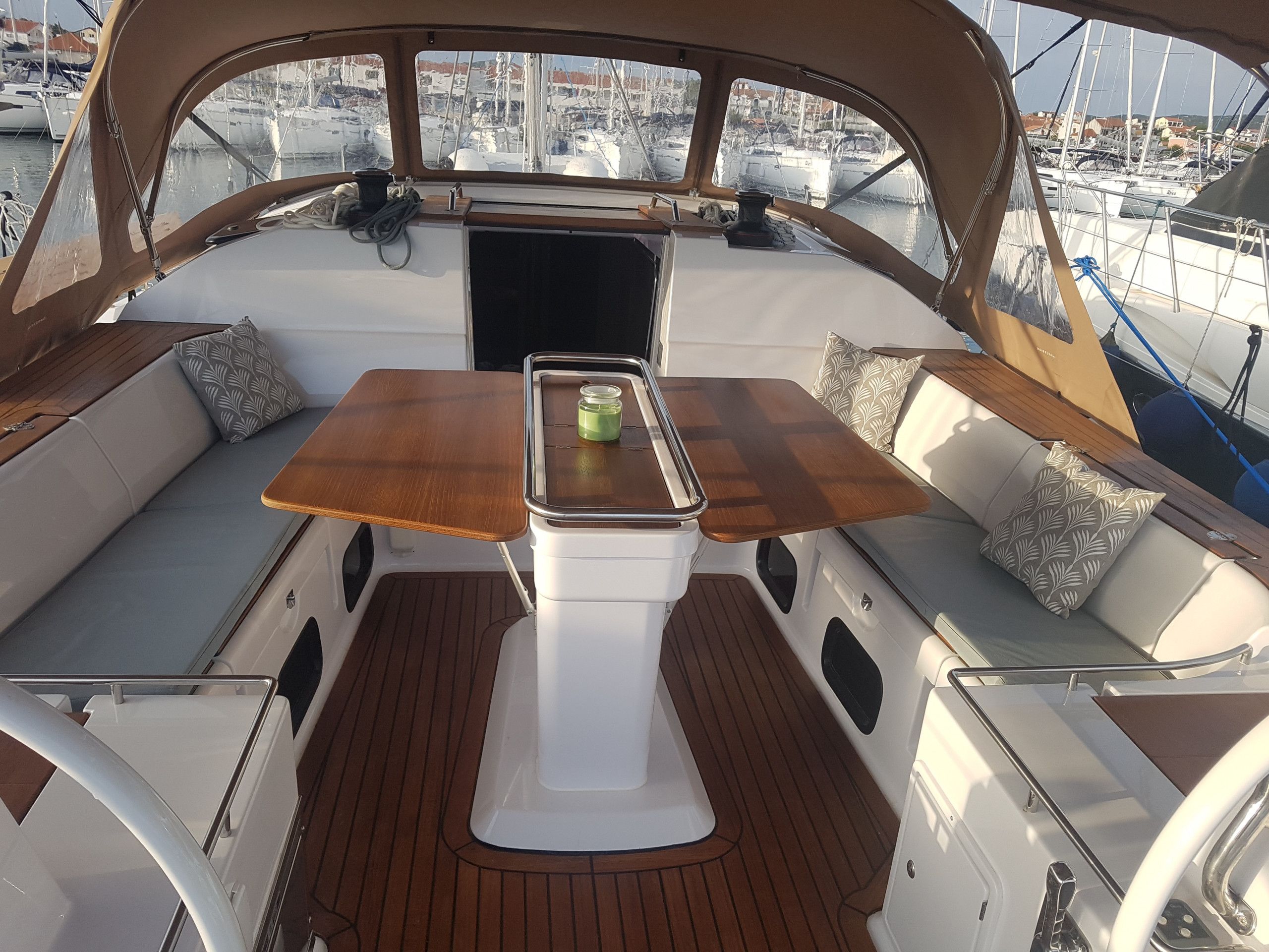 Schiffsinnere mit einem zentralen Tisch, gepolsterten Sitzgelegenheiten und Blick auf den Yachthafen.