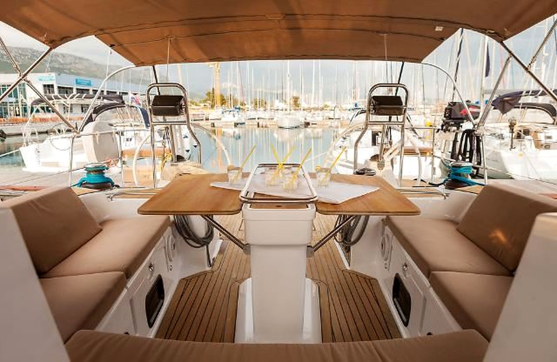 A boat deck with a covered seating area, a central table, and a view of the marina.