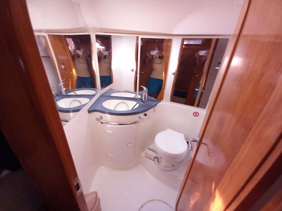 Un baño pequeño con inodoro, dos lavamanos y un espejo.