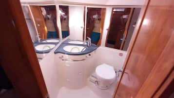 Un baño pequeño con inodoro, dos lavamanos y un espejo.