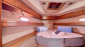 Un intérieur compact et bien éclairé, avec un lit, des oreillers et une petite fenêtre.
