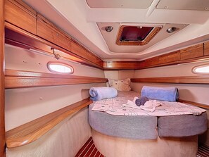 Un intérieur compact et bien éclairé, avec un lit, des oreillers et une petite fenêtre.