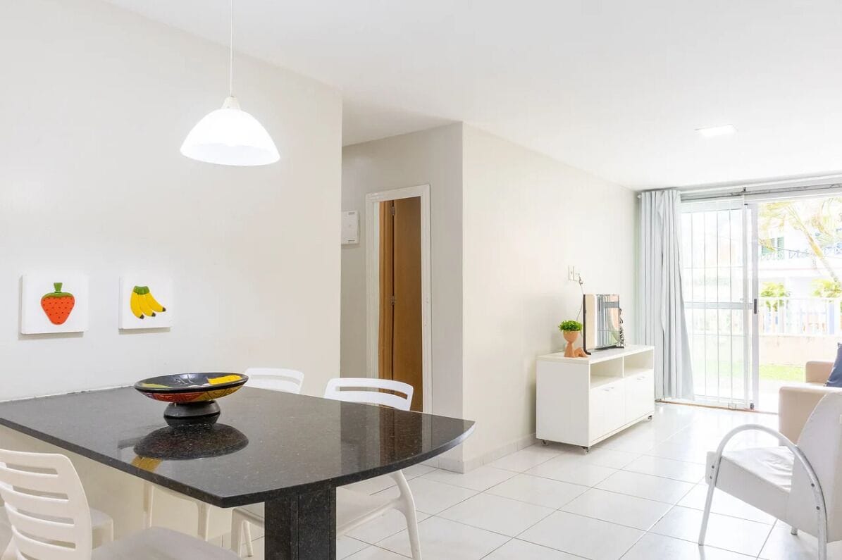 A modern dining area with a black table, white chairs, and a white pendant light.