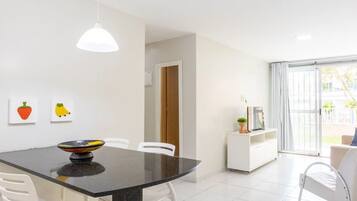 A modern dining area with a black table, white chairs, and a white pendant light.