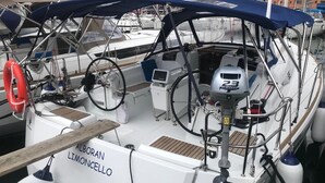 En båt med namnet ”ALBORAN Limoncello” låg förtöjd vid en småbåtshamn, och man kunde se dess ratt, kontrollpanel och flytväst.
