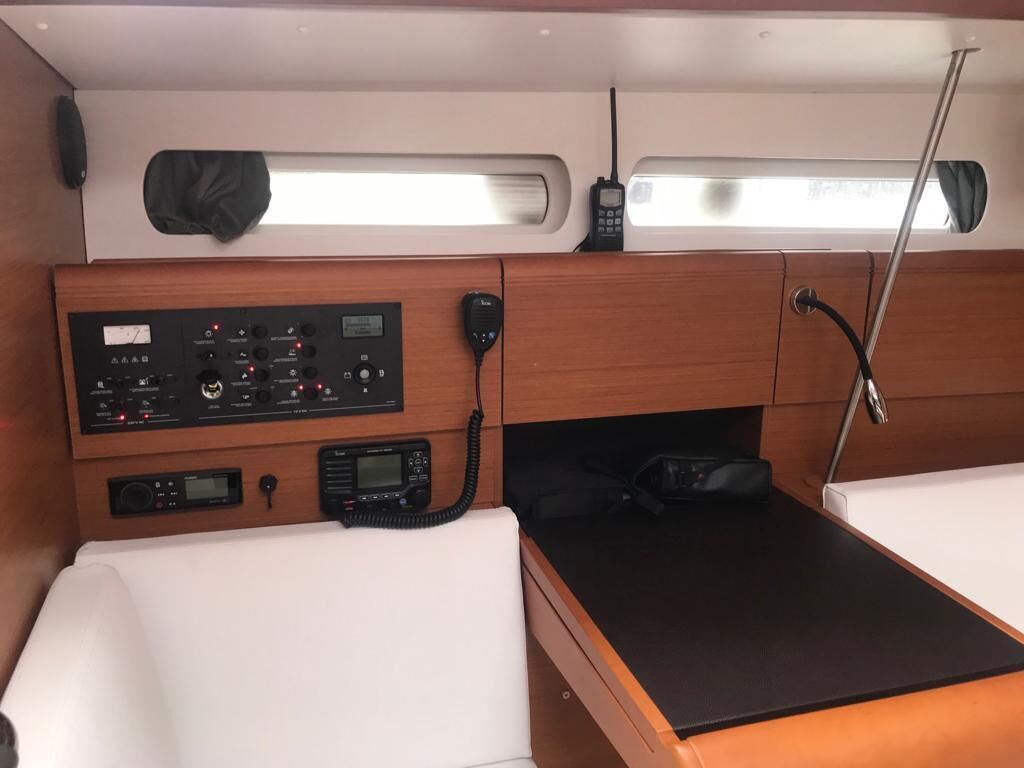 A compact cabin with a control panel, a bed, a table, and a window.