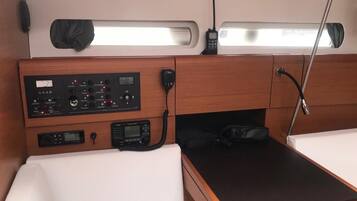 A compact cabin with a control panel, a bed, a table, and a window.