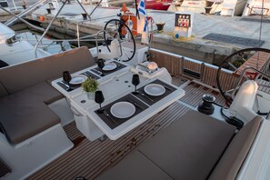 Ein Bootsdeck mit Essbereich, Steuerpult und einer Flagge.