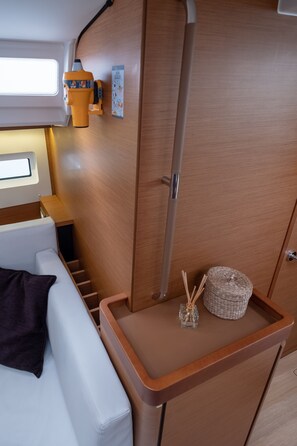 Un intérieur compact avec un canapé blanc, une petite table surmontée d’un panier en osier et d’un diffuseur de parfum en roseau, et un meuble en bois.