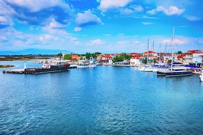 A marina with boats docked, a lighthouse, and buildings with red roofs.
