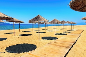 Ein Strand mit Holzstegen und Reetdachschirmen.