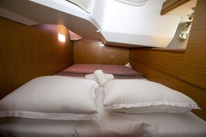 Ein gemütliches, gut beleuchtetes Blockhaus mit Bett, Kissen und kleinem Fenster.