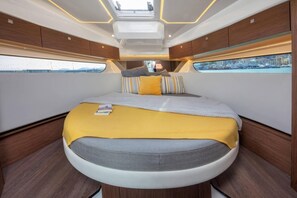 Ein modernes Interieur mit einem gebogenen Bett, Holzwandverkleidung und Blick auf eine Marina.