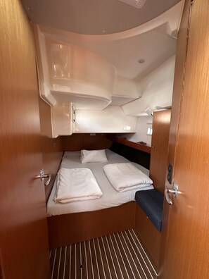 Ein gemütliches, gut beleuchtetes Abteil mit einem Bett, Stauraumschränken und einer kleinen Sitzecke.