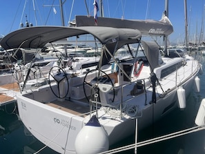 A sailboat docked at a marina with a covered cockpit, steering wheel, and various ropes and equipment. - Sun-Kissed Sailing Adventure in Split, Croatia (Kaštel Gomilica)