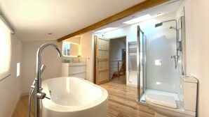 A modern bathroom with a freestanding bathtub, a glass-enclosed shower, and a toilet. - Charming house in the historic district with a garage (Foix)