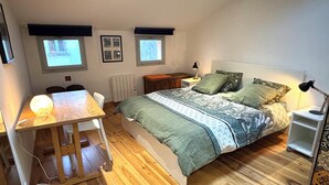 A bedroom with a bed, bedside table, desk, chair, and two windows. - Charming house in the historic district with a garage (Foix)