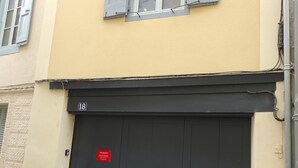 A building with a yellow facade, a black double door, and a window with shutters. - Charming house in the historic district with a garage (Foix)
