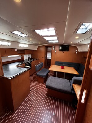 A compact galley with a sink, stove, and a small dining area with a table and benches. - Sun-Kissed Sailing Adventure in Zadar, Croatia (Bibinje)