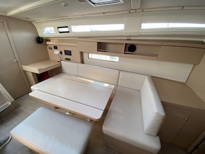 A compact boat interior with a central table, cushioned seating, and a control panel. - Sun-Kissed Sailing Adventure in Islas Sarónicas (Alimos)