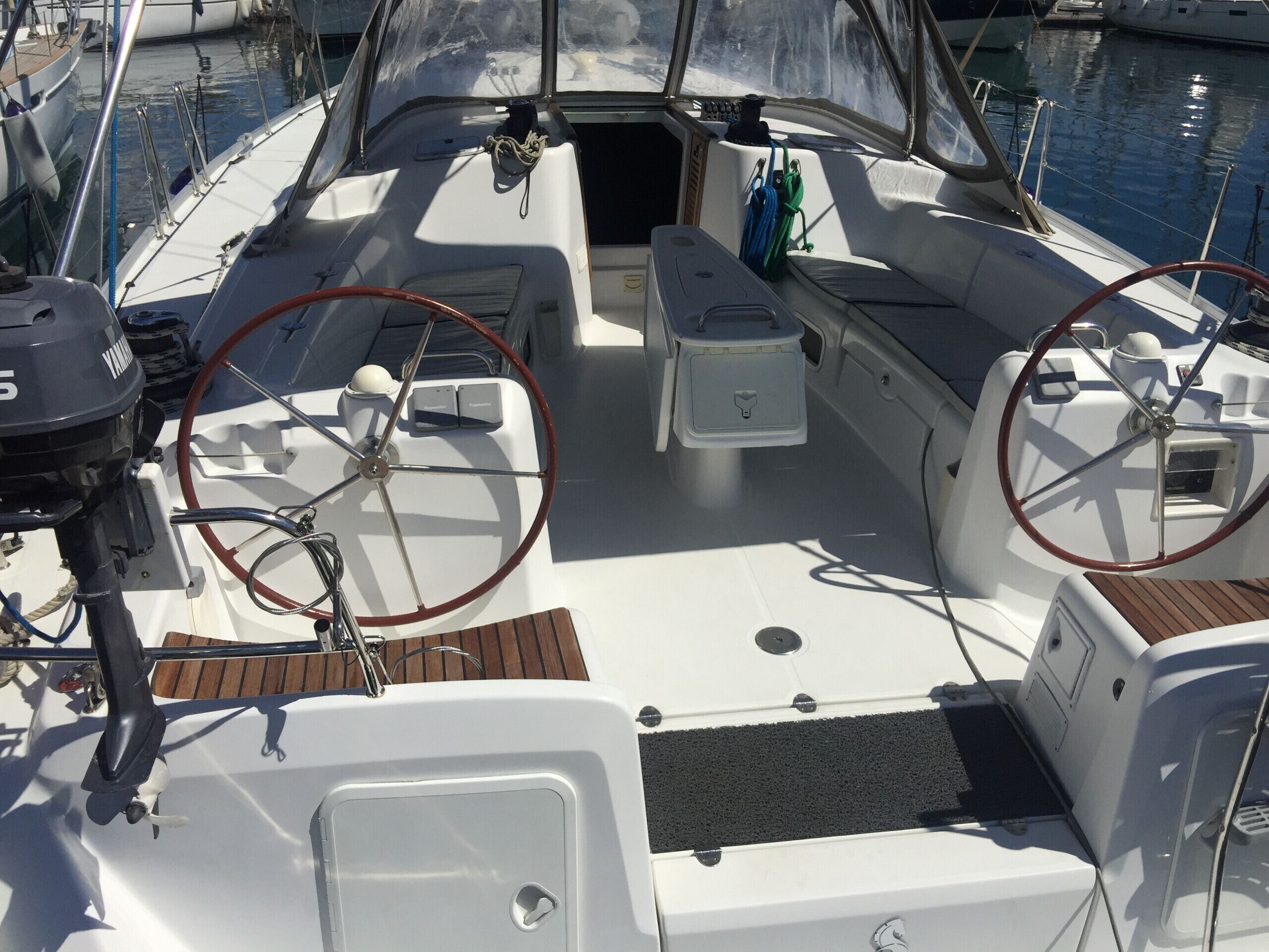 Cubierta de barco con timón, una pequeña mesa consola y una zona de estar.