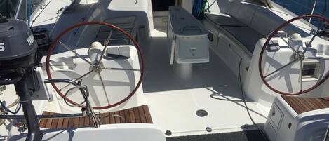 Le pont d’un bateau, avec un volant, une petite table console et un espace salon.