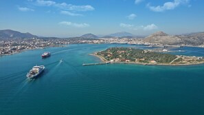 An aerial view of a coastal city with a large body of water, a ferry, and a small island with buildings.