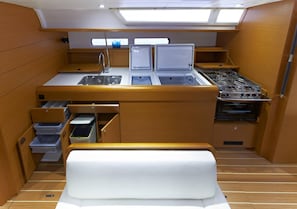 A compact galley with a sink, stove, and storage drawers. - Sun-Kissed Sailing Adventure in the Serene Saronic Islands (Elefsina)