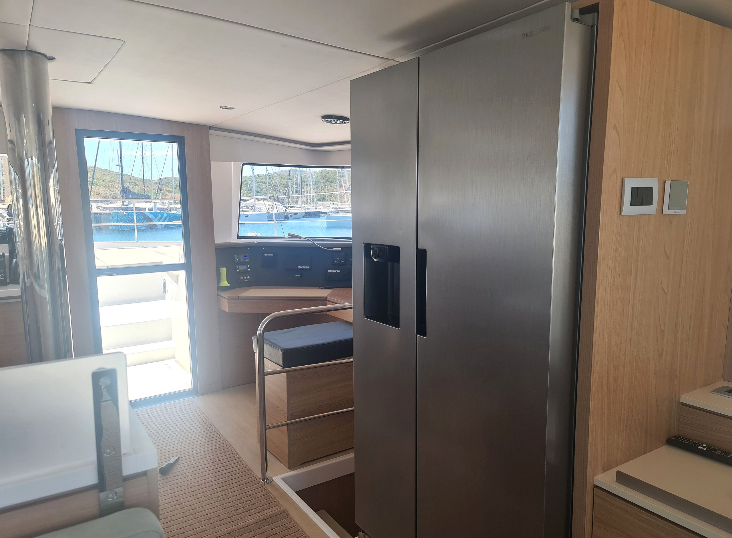 A modern kitchen with stainless steel appliances, a wooden countertop, and a view of the marina through a large window.