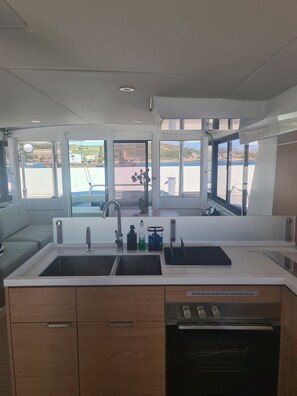 A modern kitchen with a double sink, wooden cabinets, and an oven.
