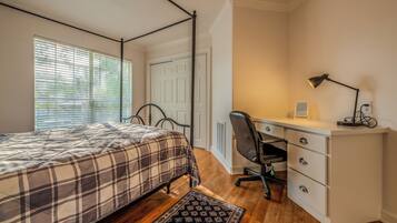 Une chambre à coucher avec un lit, un bureau, une chaise et un radiateur.